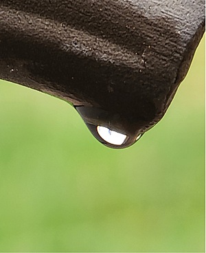 Photo showing a droplet of water forming on the end of a patio chair.