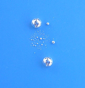 Photo showing beads of mercury on a surface.