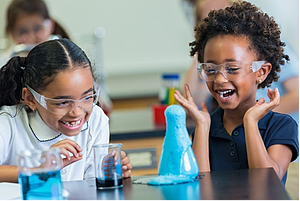 Two young children observing the elephant toothpaste demonstration.