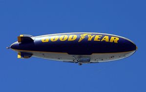 A photograph of the Good Year blimp floating behind a clear sky.