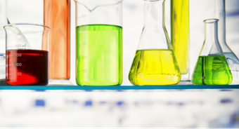 Photo of 6 colorful solutions on a lab table.