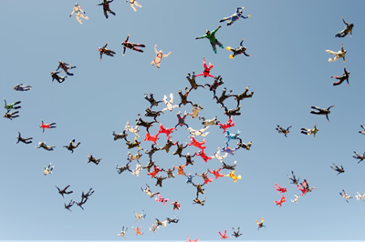 A group of skydivers in spread eagle formationi as they fall through the air.