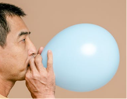 Person shown inflating a balloon.